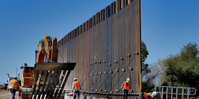 In this Sept. 10, 2019 photo, government contractors erect a section of Pentagon-funded border wall along the Colorado River in Yuma, Ariz. (AP Photo/Matt York)