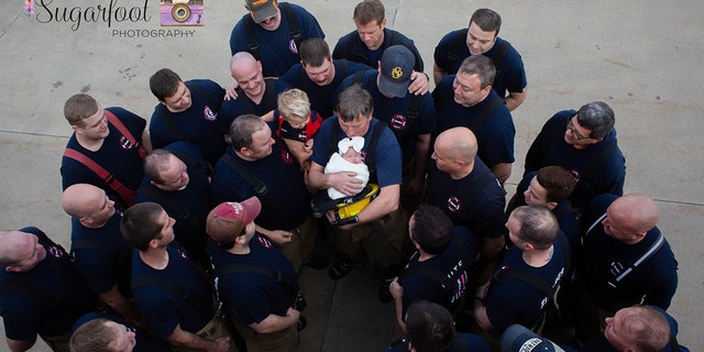 Brett Grace's grandfather, also a firefighter, holds her at a recent photo shoot with her father's fellow firefighters.