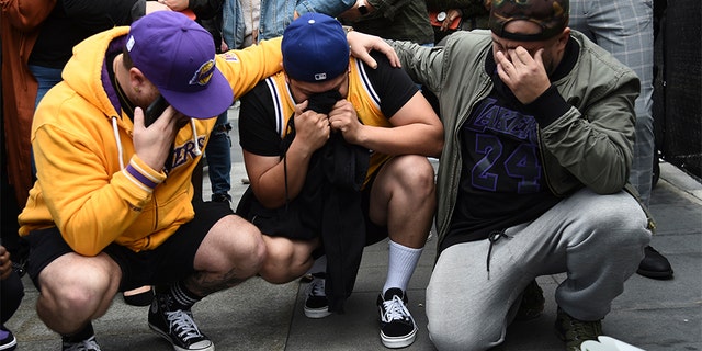 Los Angeles Laker fans Alex Fultz, from left, Eddy Rivas and Rene Alfaro mourn retired NBA star Kobe Bryant outside of the Staples Center prior to the 62nd annual Grammy Awards on Sunday, Jan. 26, 2020, in Los Angeles. Bryant died Sunday in a helicopter crash near Calabasas, Calif. He was 41. (AP Photo/Chris Pizzello)