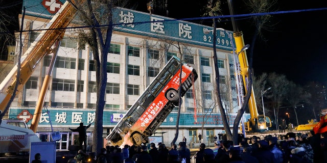 Rescue workers used a crane to raise the bus out from the hole so they could look for victims. (Ma Minyan/cnsphoto via AP)