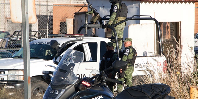 Members of the Mexican National Guard stand atop a vehicle as they keep watch outside the Cieneguillas state prison after sixteen inmates were killed and five were wounded in a brawl.