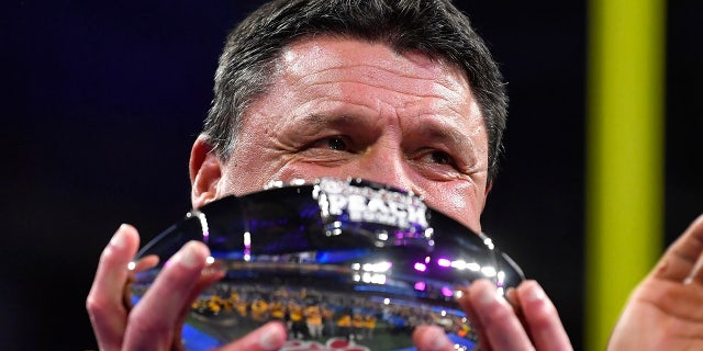 LSU coach Ed Orgeron holds the trophy after the team's Peach Bowl NCAA semifinal college football playoff game against Oklahoma, Saturday, Dec. 28, 2019, in Atlanta. LSU won 63-28. (AP Photo/John Amis)