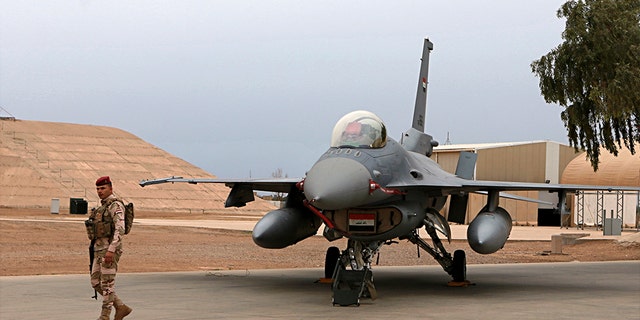 In this Feb. 13, 2018 file photo, an Iraqi army soldier stand guard near a U.S.- made Iraqi Air Force F-16 fighter jet at the Balad Air Base, Iraq. Iraqi security officials said on Jan. 12, 2020, four members of Iraq's military have been wounded by a rocket attack targeting Balad Air Base, an air base just north of Baghdad. American trainers and a company that services F-16 aircraft are present at that base. Sunday's attack by at least six rockets came just days after Iran fired ballistic missiles at two bases in Iraq housing U.S. forces, causing no casualties. (AP Photo/Khalid Mohammed)