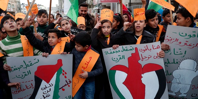 Protesters hold placards as others wave their national flags during a protest against the Mideast plan announced by President Trump, at Jebaliya refugee camp, Gaza Strip, Thursday, Jan. 30, 2020. (AP Photo/Adel Hana)