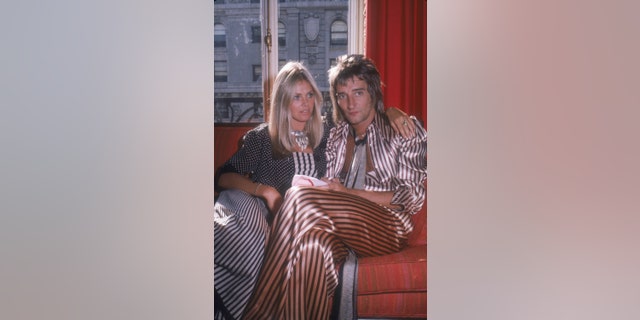 British musician Rod Stewart and his girlfriend, Swedish actress Britt Ekland, sitting on a sofa in a hotel room while on a promotional tour in support of Stewart's album 'Atlantic Crossing,' New York, New York, July 29, 1975.