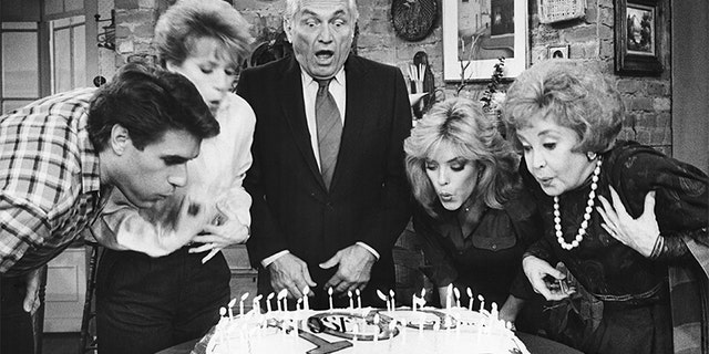 Actor Ted Knight (center) is joined by cast members L-R Jim J. Bullock, Nancy Dussault, Lydia Cornell and Audrey Meadows in blowing out the candles on a cake in celebration of the taping of the 100th episode of "Too Close for Comfort" at Metromedia Television Studios on November 30, 1984, Los Angeles, California.