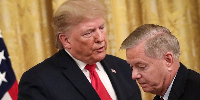President Donald Trump speaks to Sen. Lindsey Graham, R-S.C., during an event about judicial confirmations in the East Room of the White House. (Photo by Drew Angerer/Getty Images)