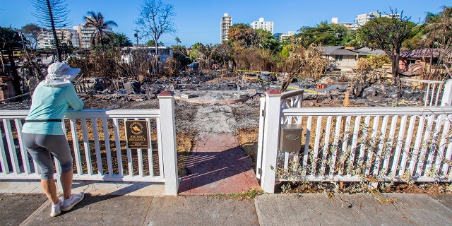 In this photo taken Thursday, Jan. 23, 2020, a woman looks at the rubble of a historic residence after a fire destroyed the home following a shooting in Honolulu over the weekend. Residents have been allowed to return to their homes following a suspected landlord-tenant dispute where two police officers were fatally shot and two others died. A fire that followed last Sunday's violence destroyed several homes. (Dennis Oda/Honolulu Star-Advertiser via AP)