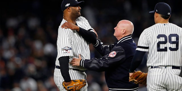 Oct 17, 2019; Bronx, NY, USA; New York Yankees pitcher CC Sabathia (52) reacts as he examined by trainer Steve Donohue after suffering an apparent injury against the Houston Astros as third baseman Gio Urshela (29) looks on during the eighth inning of game four of the 2019 ALCS playoff baseball series at Yankee Stadium.