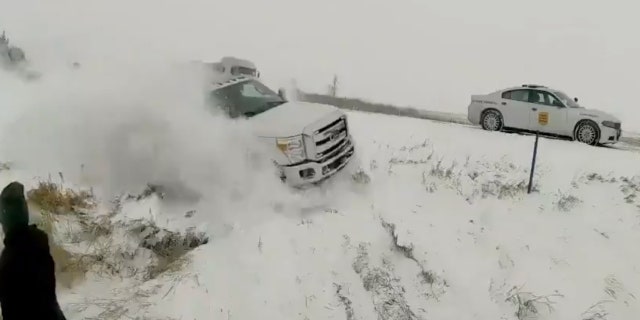 The video released by the Iowa State Patrol shows a state police officer and another man almost being hit by a vehicle that lost control on a snowy road.
