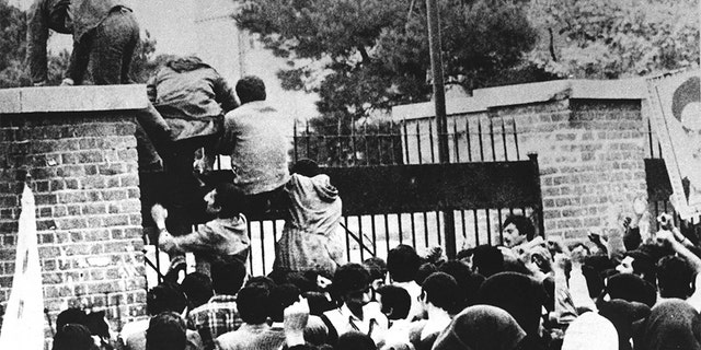 Iranian students climb over the wall of the US embassy in Tehran 04 November 1979.