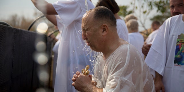 A Christian pilgrim takes part in baptism in the Jordan river during the Orthodox Feast of the Epiphany at Qasr el Yahud, Saturday, Jan. 18, 2020. (AP Photo/Majdi Mohammed)