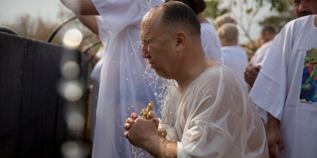 A Christian pilgrim takes part in baptism in the Jordan river during the Orthodox Feast of the Epiphany at Qasr el Yahud, Saturday, Jan. 18, 2020. (AP Photo/Majdi Mohammed)