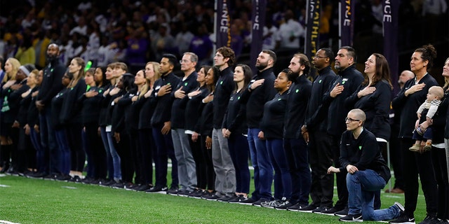 A teacher from the Extra Yard for Teachers charity kneels during the National Anthem prior to the Clemson v LSU game on January 13, 2020 in New Orleans, Louisiana.