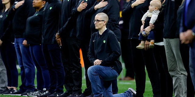 A teacher from the Extra Yard for Teachers charity kneels during the National Anthem prior to the Clemson v LSU game in the College Football Playoff National Championship.