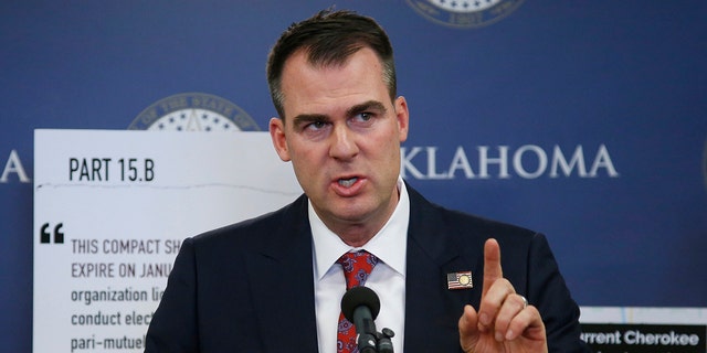 FILE - In this Dec. 17, 2019, file photo, Oklahoma Gov. Kevin Stitt gestures during a news conference in Oklahoma City. Stitt on Thursday, Jan.23, 2020, banned state-funded travel to the state of California, saying it's in response to similar bans California has put in place on travel to the Sooner State. The first-term Republican issued an executive order that prohibits all non-essential travel by state employees to California, with exceptions for business recruiting trips, college sports games and trips by schools to participate in programs.(AP Photo/Sue Ogrocki, File)