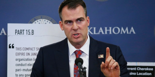 FILE - In this Dec. 17, 2019, file photo, Oklahoma Gov. Kevin Stitt gestures during a news conference in Oklahoma City. Stitt on Thursday, Jan.23, 2020, banned state-funded travel to the state of California, saying it's in response to similar bans California has put in place on travel to the Sooner State. The first-term Republican issued an executive order that prohibits all non-essential travel by state employees to California, with exceptions for business recruiting trips, college sports games and trips by schools to participate in programs.(AP Photo/Sue Ogrocki, File)