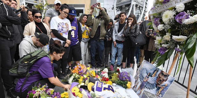 Valerie Samano, left, placing flowers at a memorial near the Staples Center after the death of Laker legend Kobe Bryant on Sunday. (AP Photo/Michael Owen Baker)
