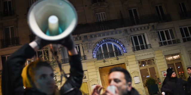 A protestor speaks in a megaphone during a demonstration in front of the Bouffes du Nord theatre in Paris on January 17, 2020 as the French president attends a play. - Protestors demonstrate against French president's policies on pension reform. (Photo by Lucas BARIOULET / AFP) (Photo by LUCAS BARIOULET/AFP via Getty Images)