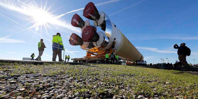 Security and safety personnel walk with the core stage of NASA's Space Launch System rocket that will be used for the Artemis 1 Mission as it is moved to the Pegasus barge at the NASA Michoud Assembly Facility where it was built in New Orleans. (AP Ph