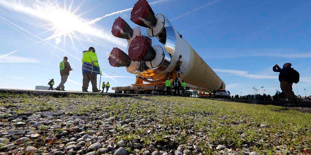 Security and safety personnel walk with the core stage of NASA's Space Launch System rocket, that will be used for the Artemis 1 Mission, as it is moved to the Pegasus barge, at the NASA Michoud Assembly Facility where it was built, in New Orleans. (AP Photo/Gerald Herbert)