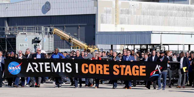 Workers and contractors who worked on the core stage of NASA's Space Launch System rocket, that will be used for the Artemis 1 Mission, follow the rocket as it is transported to the Pegasus barge at the NASA Michoud Assembly Facility where it was built, in New Orleans. (AP Photo/Gerald Herbert)