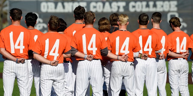 The Orange Coast College baseball players stands for the national anthem while wearing shirts with the number 14 on their backs for late head coach John Altobelli, who died in a helicopter crash alongside former NBA basketball player Kobe Bryant in Costa Mesa, Calif., Tuesday, Jan. 28, 2020. (AP Photo/Kelvin Kuo)