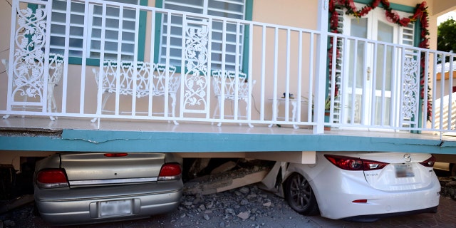 Cars were crushed under a home in Guanica that collapsed after Monday's earthquake. (AP Photo/Carlos Giusti)