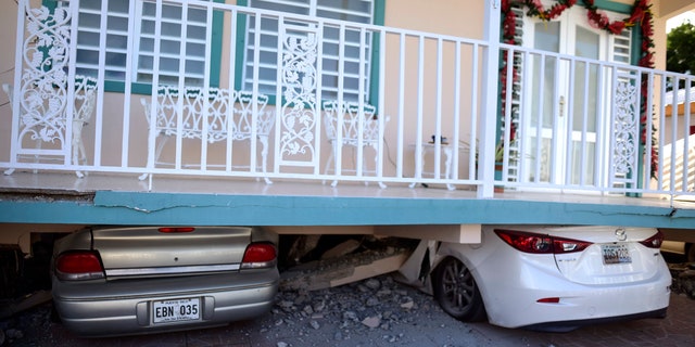 Cars are crushed under a home that collapsed after an earthquake hit Guanica, Puerto Rico, Monday, Jan. 6, 2020.