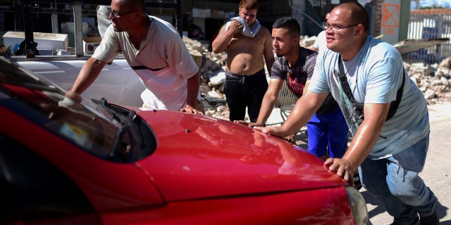Men move a car stalled outside Ely Mer Mar hardware store, which partially collapsed after an earthquake struck Guanica, Puerto Rico, Tuesday, Jan. 7, 2020.
