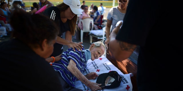 96 years-old Martin Velez gets placed in a bed by neighbors outside a shelter afraid of aftershocks, after an earthquake in Guanica, Puerto Rico, Tuesday, Jan. 7, 2020.