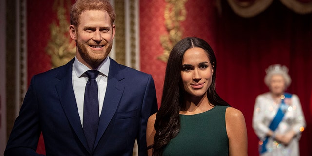 The figures of Britain's Prince Harry and Meghan, Duchess of Sussex, left, are moved from their original positions next to Queen Elizabeth II, Prince Philip and Prince William and Kate, Duchess of Cambridge, at Madame Tussauds in London following their bombshell announcement.