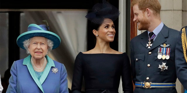 FILE - In this Tuesday, July 10, 2018 file photo Britain's Queen Elizabeth II, and Meghan the Duchess of Sussex and Prince Harry watch a flypast of Royal Air Force aircraft pass over Buckingham Palace in London. (AP Photo/Matt Dunham, File)