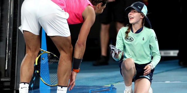 Spain's Rafael Nadal hands a ball girl his bandana after a ball hit her during his second-round match against Federico Delbonis of Argentina at the Australian Open tennis championship in Melbourne, Thursday, Jan. 23, 2020. (AP Photo/Dita Alangkara)