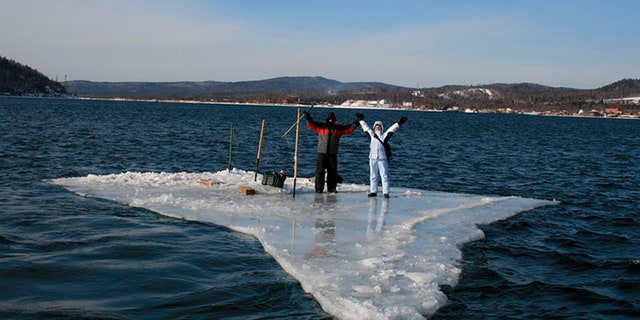 In this Tuesday, Jan. 28, 2020 photo released by the Russia Emergency Situations Ministry press service, showing two fishermen using a smaller piece of ice as a raft and try to row to the land.