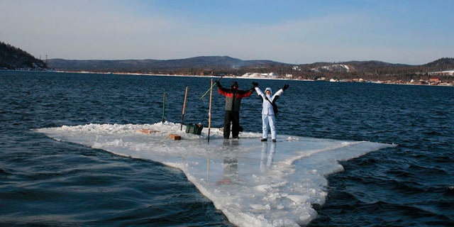 In this Tuesday, Jan. 28, 2020 photo released by the Russia Emergency Situations Ministry press service, showing two fishermen using a smaller piece of ice as a raft and try to row to the land.