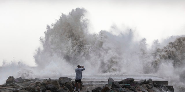 A man takes a snapshot of the waves hitting the breakwater in Barcelona, Spain, Wednesday, Jan. 22, 2020.