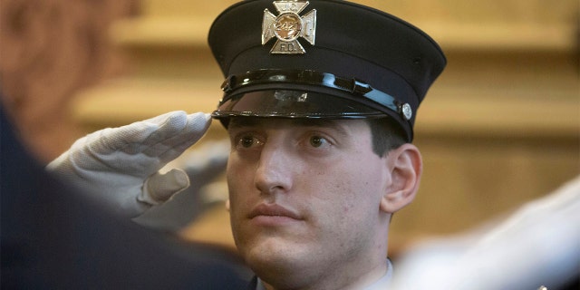 In this photo provided by the Jersey City, N.J. Mayor's Office, Sam Springsteen salutes during a ceremony as he is sworn in as a Jersey City firefighter. (Jennifer Brown/Jersey City Mayor's Office via AP)