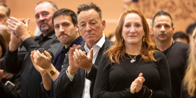 Bruce Springsteen, center, and Patti Scialfa, right, applaud as their son Sam Springsteen is sworn in as a Jersey City, N.J., firefighter. (Jennifer Brown/Jersey City Mayor's Office via AP)