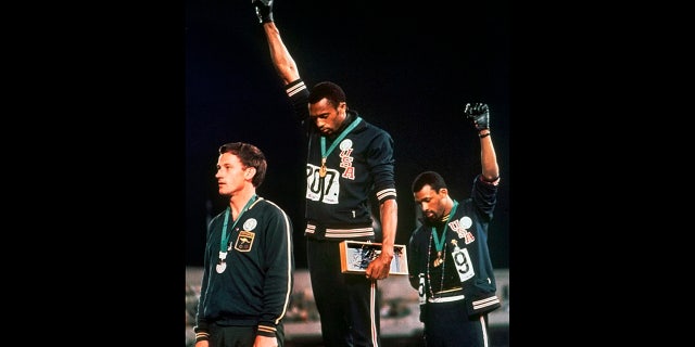 U.S. athletes Tommie Smith, center, and John Carlos, right, raise their gloved fists after Smith received the gold and Carlos the bronze for the 200 meter run at the Summer Olympic Games in Mexico City, Oct. 16, 1968. (Associated Press)