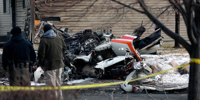 People look at the debris from a small private plane that crashed in a residential area Wednesday, Jan. 15, 2020, in Roy, Utah. The small plane crashed Wednesday, killing the pilot as the aircraft narrowly avoided hitting any townhomes, authorities said. (Ben Dorger/Standard-Examiner, via AP)