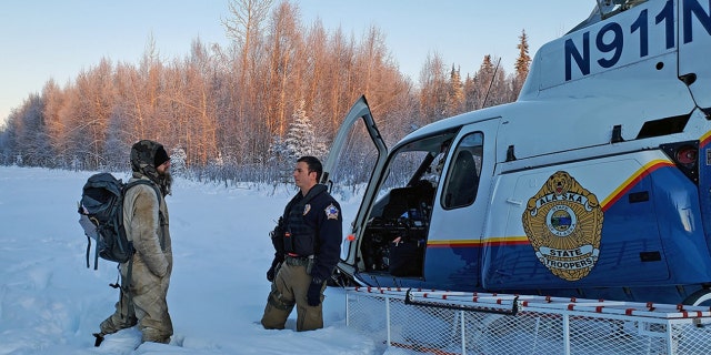Tyson Steele, left, speaks with Helo 3 Tactical Flight Officer Zac Johnson upon being rescued after more than 20 days stranded in the wilderness after his cabin burned down.