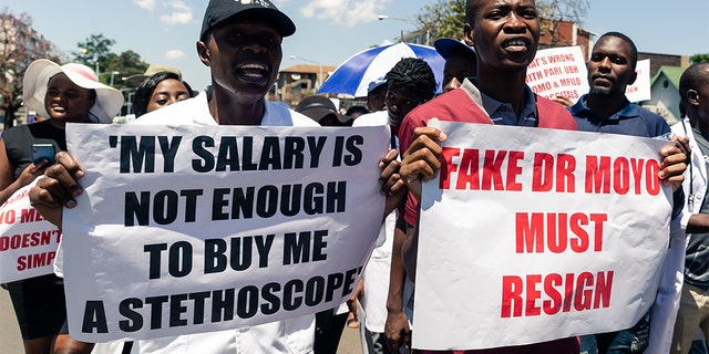 Doctors hold banners during a protest march by senior medical doctors in Harare in December 2019. The doctors petitioned Zimbabwe's parliament, demanding improved working conditions and the reinstatement of 448 junior doctors fired for taking part in a two-month long strike over low salaries. (Photo by Jekesai NJIKIZANA / AFP) (Photo by JEKESAI NJIKIZANA/AFP via Getty Images)