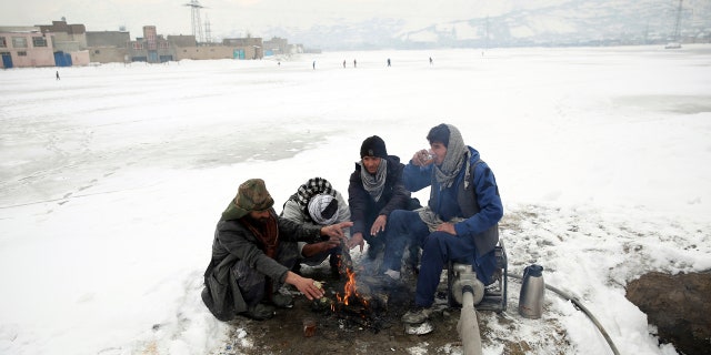 People sit around a fire to warm themselves after a heavy snowfall in Kabul, Afghanistan, Tuesday, Jan. 14, 2020.