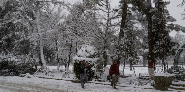 In this Sunday, Jan. 12, 2020, photo, people walk on a road during heavy snow fall in Quetta, capital of Pakistan's southwestern Baluchistan province.