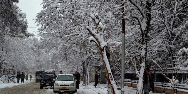 In this Sunday, Jan. 12, 2020, photo, people walk on a road during heavy snow fall in Quetta, capital of Pakistan's southwestern Baluchistan province.