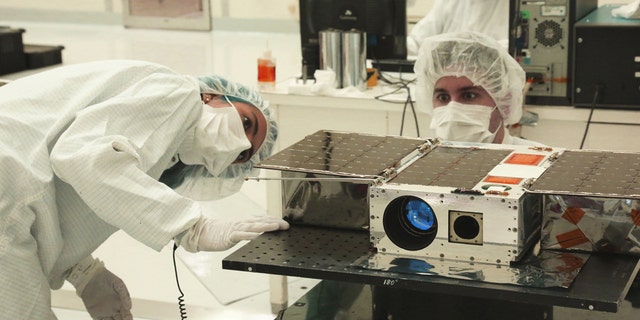 Left to right: Electrical Test Engineer Esha Murty and Integration and Test Lead Cody Colley prepare the ASTERIA spacecraft for mass-properties measurements in April 2017 prior to spacecraft delivery ahead of launch. ASTERIA was deployed from the International Space Station in November 2017. Credit: NASA/JPL-Caltech