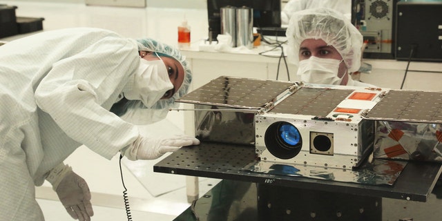 Left to right: Electrical Test Engineer Esha Murty and Integration and Test Lead Cody Colley prepare the ASTERIA spacecraft for mass-properties measurements in April 2017 prior to spacecraft delivery ahead of launch. ASTERIA was deployed from the International Space Station in November 2017. Credit: NASA/JPL-Caltech