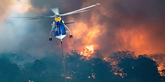 In this Monday, Dec. 30, 2019 photo provided by State Government of Victoria, a helicopter tackles a wildfire in East Gippsland, Victoria state, Australia.