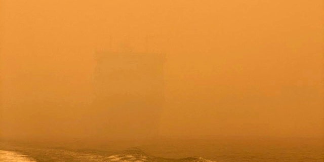 In this photo provided by the Australian Defence Force, HMAS Choules appears as a ghostly figure through smoke haze off the coast of Mallacoota, Australia, Thursday, Jan. 2, 2020.